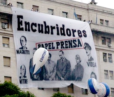 Bandera sobre papel prensa y dueños clarin con la fraseencubridores